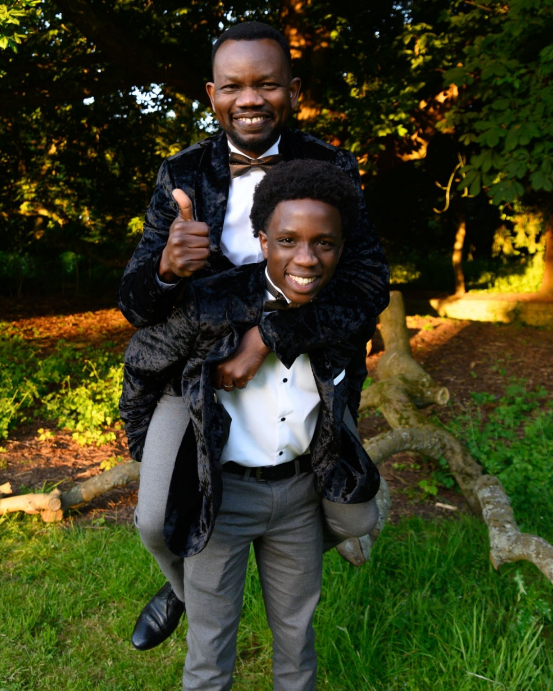 Father and son sharing a joyful piggyback moment in black velvet tuxedos