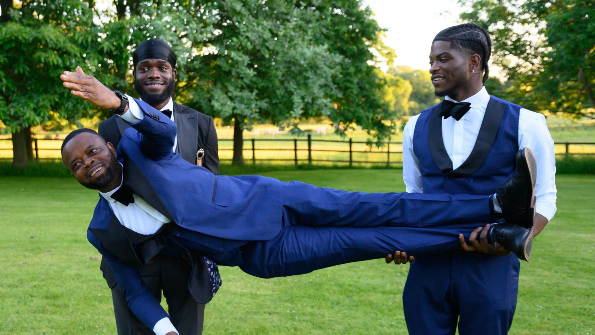 Sons lifting father horizontally like a superhero outdoors